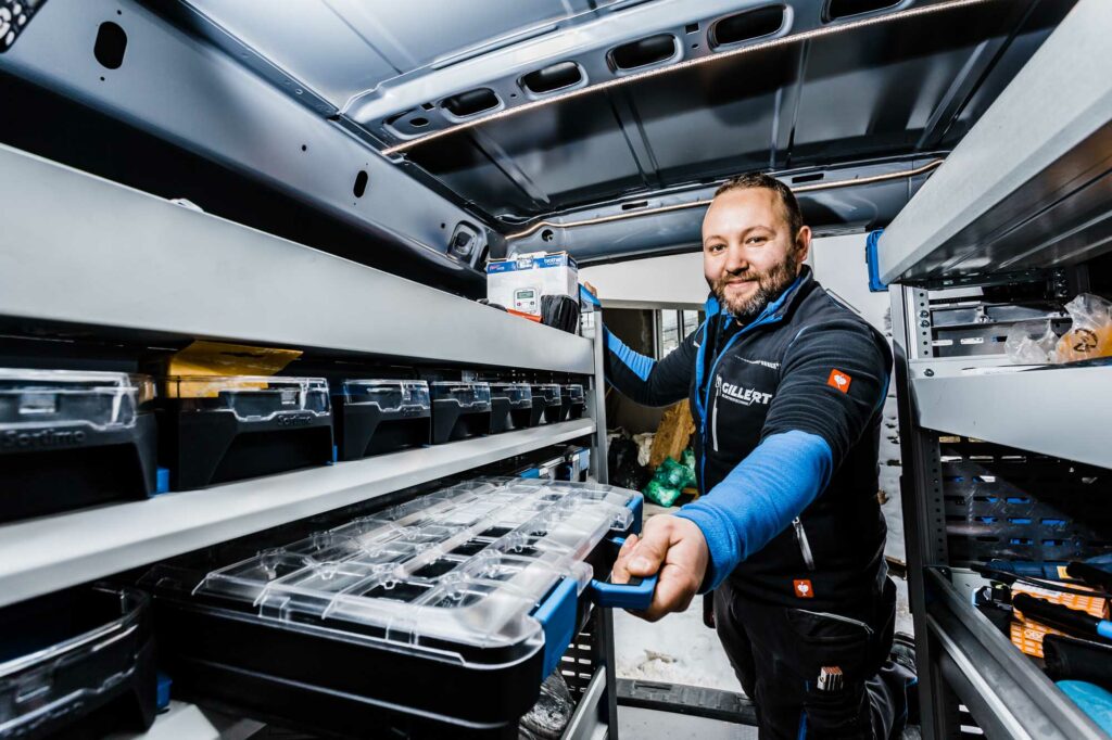 Handwerker sortiert Werkzeug im Transporter.