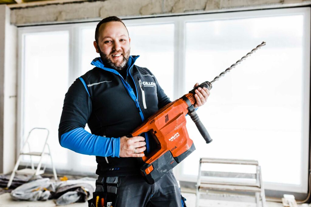 Fröhlicher Handwerker mit riesigem Bohrer.
